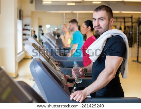 Fitness confidence. Portrait of young and handsome man training on treadmill. Muscles and confidence