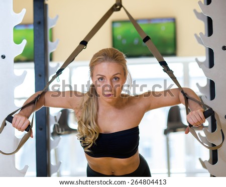 Great suspension training. Young and pretty athlete girl is having a suspension workout in a gym