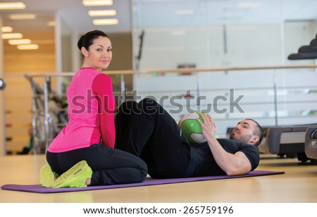 Intensive training together. Couple of young and beautiful people is having workout in a gym. Both are having abdominals training. Perfect shape. Sportsmen. Good workout in a gym