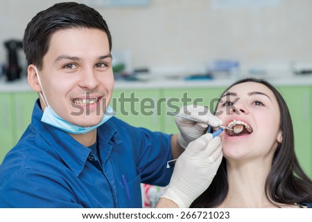 Healthy teeth and dental healthcare. Confident professional doctor dentist is working with pretty female patient. Doctor stomatologist is wearing medical clothing. Stomatology hygienist.