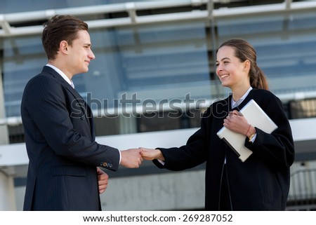 Well done business deal. Portrait of two confident and motivated partners. Man and woman are shaking hands, both have agreement on essential business project. Outdoor business concept