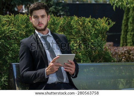 Business confidence. Portrait of motivated businessman. Leader is working with tablet. Outdoors business concept