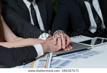 Good business team work. Team of businessmen are touching and shaking hands. Laptops are on the background. Business concept