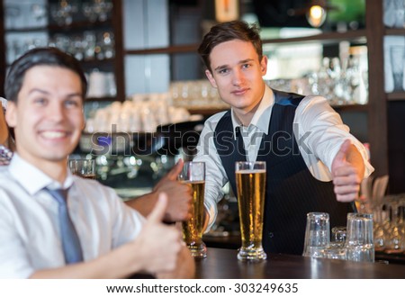 Beer evening in a pub. Portrait of young and handsome barman in a pub. Beer glasses.  Beer football pub bar concept.