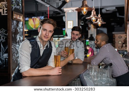 Beer evening in a pub. Portrait of young and handsome man drinking beer in a pub with his friends. Beer glasses.  Beer football pub concept.