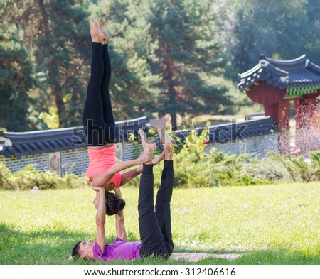Perfect acroyoga. Beautiful young couple is balancing doing acro-yoga. Pair yoga concept. Yoga flexibility outdoor class workout