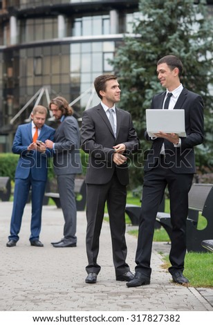 Business confidence. Portrait of motivated businessman in formal suit at work. His business partners are on background. Business outdoors