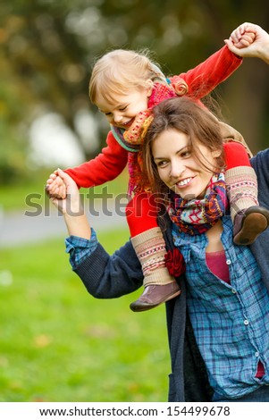 Little girl and her mother playing in the autumn park