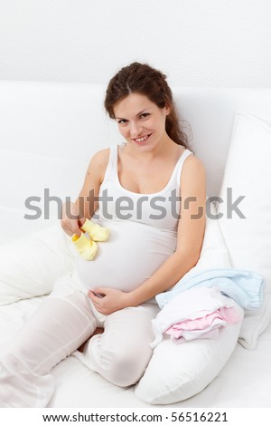 Beatiful pregnant woman choosing baby\'s clothes