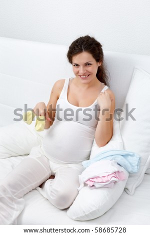 Beautiful pregnant woman choosing baby\'s clothes