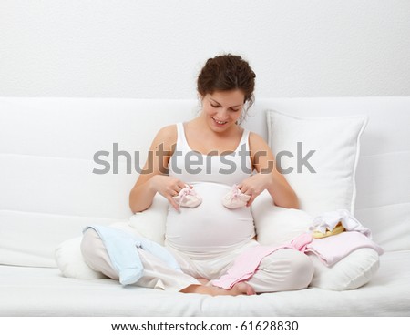 Beautiful pregnant woman choosing baby\'s clothes