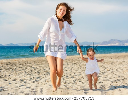 Mother and little daughter running on the beach