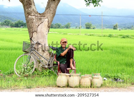 Dien Bien Phu, Dien Bien, Vietnam August 6, 2014: A farmer sitting sells handcrafted items beside a road.