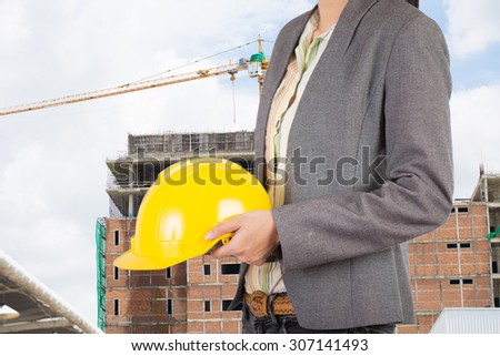 Engineer holding yellow helmet for workers security on background