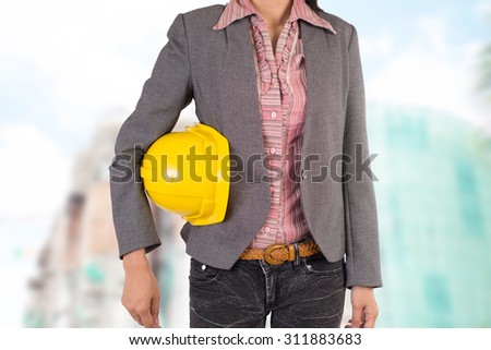 Engineer holding yellow helmet for workers security on background