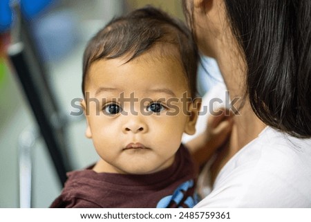 Similar – Image, Stock Photo Curious beautiful baby boy in blue body lying on playing mat, looking in the camera
