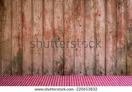Old Barn door with faded paint for use as a background with red and white checkered tablecloth in foreground.