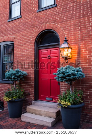 Red door entry to town home with lantern on.