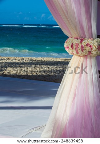 View of beautiful flowers at beach alter framing the ocean for a destination wedding shot vertical.