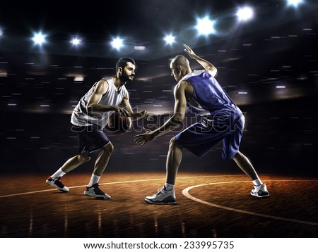 Two basketball players in action in gym in lights