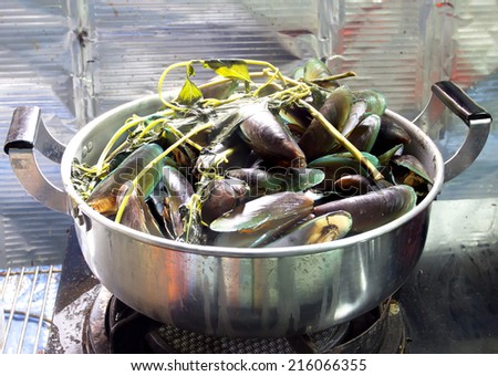 Mussels steamed with vegetables in a stainless steel pot.