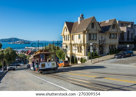 Powell Hyde cable car, a group of tourist attraction, descends a steep hill overlooking Alcatraz prison and SF bay on April 13, 2015 in San Francisco, USA