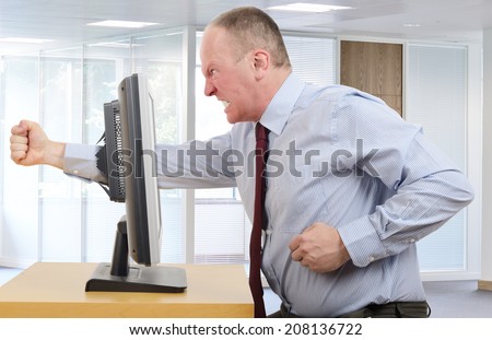 Businessman in office in a rage with a computer screen