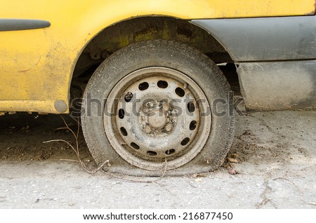 Flat tire of old yellow car on the parking