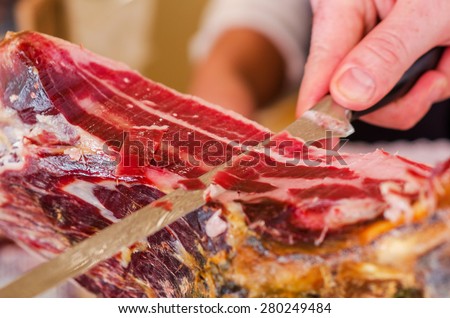Chef slices serrano ham. Jamon Serrano. Typical Spanish delicatessen (prosciutto)