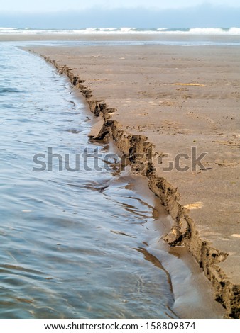 A Line of Wet Sand Eroding at the Beach at the Water\'s Edge