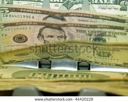An electronic money counter processing US $5 bills