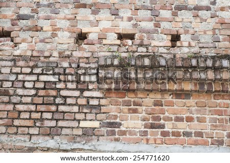 An old colonial township with some defaced brick walls among them / Old brick wall / Grunge and fallen plaster exposing bricks within