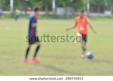 blur young children playing soccer on green soccer pitch