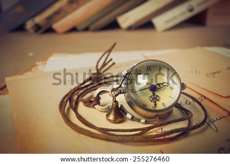 Old-styled pocket or pendant watch with old string around them on background of writing-paper and old books