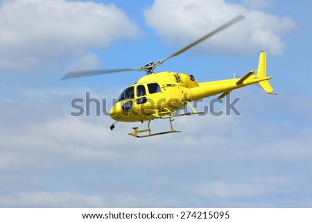 Helicopter rescue, Yellow helicopter in the air while flying on blue sky. All logos and text removed.
