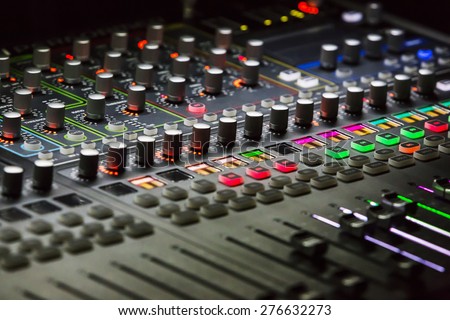 Audio mixer mixing board fader and knobs with selective focus on central buttons, Music mixing console with backlit buttons