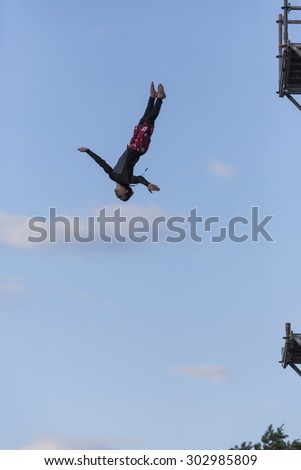 Unknown young man jumping into a lake in the quarry of towers, 30 July 2015. Pribram, Czech Republic