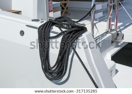 Close-up of a mooring rope with a knotted end tied around a cleat on a wooden pier. Nautical mooring rope