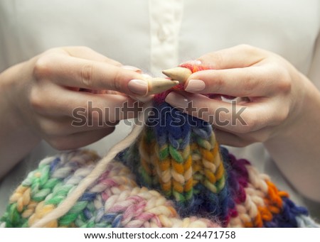 Knitting a colorful scarf, closeup of the hands