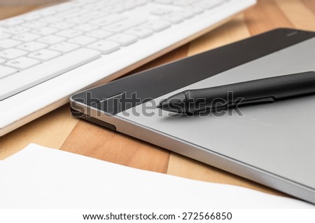 Graphic tablet, pen and keyboard. Selective focus on pen edge.