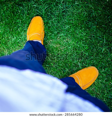 A shot of blue trousers and yellow boat or deck shoes - loafers. Done with a retro film filter and vignetting. Selective focus on shoes.