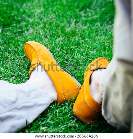A shot of linen trousers and yellow boat or deck shoes - loafers. Done with a retro film filter. Selective focus on shoes.