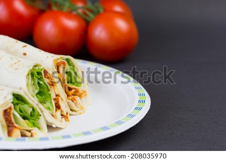 Fajitas on paper plate with tomatoes on background.