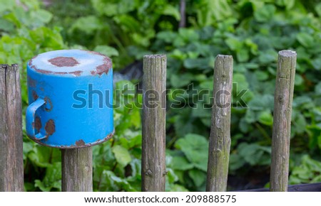 Blue rusty pot on wooden fence post