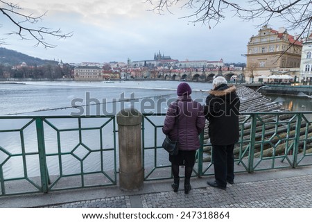 Two seniors are watching Prague panorama and feeding flying gulls. Wide angle shot with copy space