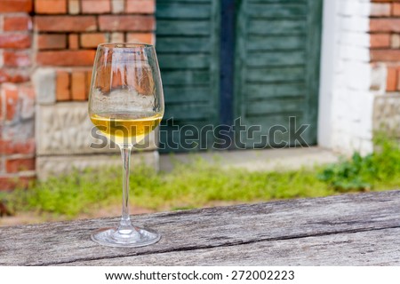 Horizontal Image of a wine glass with golden and little cloudy 2014 Chardonnay in it.Sharp focus on wine glass with blurred background and copy space on right