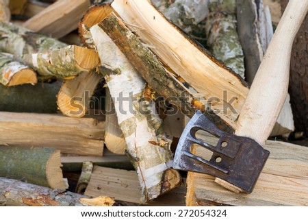 Chopped logs with axe on top of them. Mixture of cherry, maple and birch wood. All in sharp focus