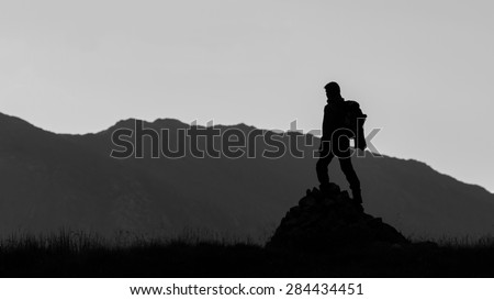 Black and white silhouette of hiker on the top of the hill. Lifestyle concept