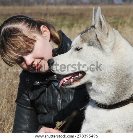 Young beautiful girl playing with a dog. Playing with the dog on the field. Siberian husky.