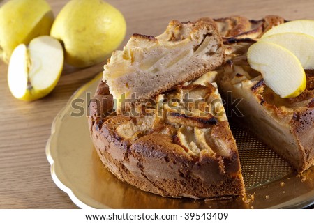 An Apple cake decorated with apple slices on a wooden table with fresh fruit